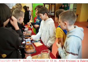 Uczniowie klasy 6c sprzedają swoje produkty podczas kiermaszu.